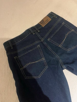Mörkblå jeans från 24/7 New Four Seasons - Snygga mörkblå jeans med raka ben och kontrastsömmar. Klassisk femficksmodell med unika detaljer på bakfickorna och läderpatch i midjan. Perfekta för dig som gillar stilrena och tidlösa jeans. Hör av dig vid intresse 💛