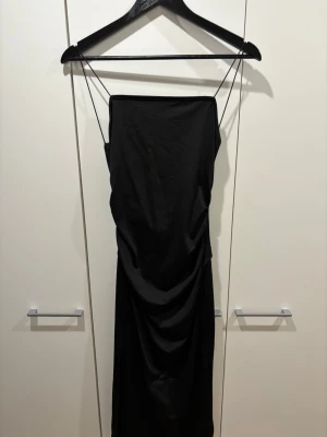 Svart långklänning med slits - Svart långklänning med tunna axelband och slits på sidan. Aldrig använt!
