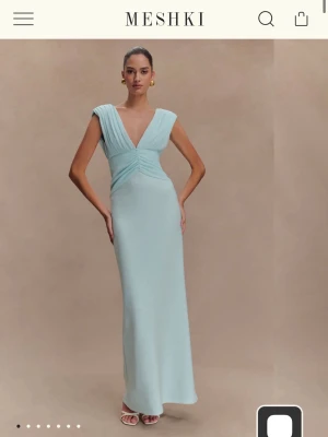 Ljusblå långklänning från Meshki - Pris går att diskutera!!! Säljer denna eleganta ljusblå långklänning från Meshki med djup v-ringning och breda axelband. Den är helt oanvänd och har lappen kvar. Klänningen har omlott-detaljer vid midjan och öppen rygg. Perfekt för dig som vill ha en stilren och modern look. Ursnygg!! 