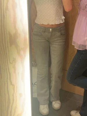 Grå bootcut jeans från Gina Tricot - Säljer ett par gråa jeans från Gina Tricot i storlek 158. De har bootcut-modell med låg midja och klassisk femficksdesign. Jeansen är i mjukt denimtyg och har dubbla knappar framtill. Perfekta för dig som gillar en avslappnad och trendig look.