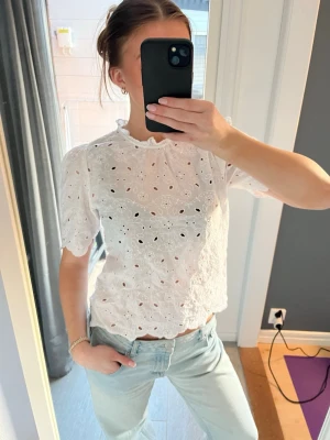 Vit blus med korta ärmar - Säljer en vit blus med broderade detaljer. 🌷Blusen har korta ärmar och en söt volangkant vid halsen.