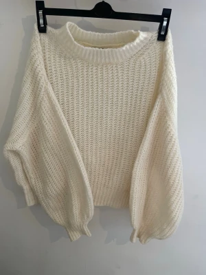 Stickad tröja från Gina tricot - Mysig vit stickad tröja med oversized passform och breda ärmar. Tröjan har grovstickad struktur, rund halsringning och ribbade muddar vid ärmslut och nederkant. Perfekt för lager-på-lager och en chill look.