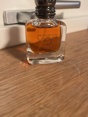 Stronger With You intensely 2 ml  - En snygg parfymflaska från Armani, Stronger With You. Flaskan är genomskinlig med rundade kanter och innehåller en bärnstensfärgad vätska. Stilig metallkork och modern design gör den till ett måste i parfymhyllan.