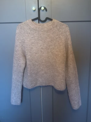 Beige stickad tröja från Zara - Mysig beige stickad tröja från Zara med rund halsringning och lång ärm. Aldrig använd. Tröjan har en något boxig och croppad passform, perfekt att styla med höga jeans. Materialet är fluffigt och mjukt, vilket ger en avslappnad och trendig look. 