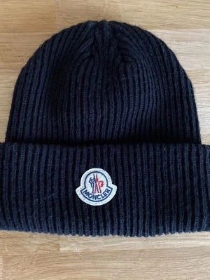 Svart Moncler mössa - Fin Moncler mössa som passar jätte mysig och skön, håller faktiskt varm också! Pris går att diskuteras