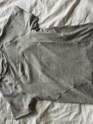 Grå funktions-tshirt från Aimn - Snygg grå funktions-tshirt från Aimn med diskret logga på bröstet. T-shirten har korta ärmar, rund halsringning och är tillverkad i ett mjukt syntetmaterial som andas. Perfekt för dig som gillar en sportig och clean stil.