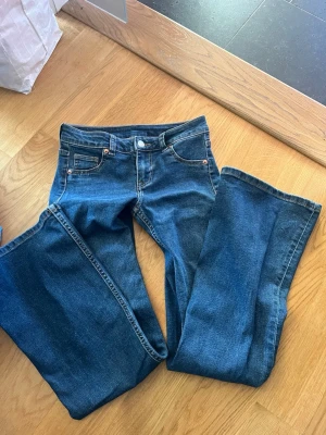 Blå bootcut jeans  - Säljer ett par klassiska blå bootcut jeans med fem fickor och snygga kontrastsömmar. Jeansen har låg midja och är tillverkade i denim med stretch för extra komfort. Perfekta för dig som gillar en tidlös och avslappnad look. Köpta på hm förra sommaren och använts få gånger. Säljer pga att de är för korta för mig. Skriv för mått och fler bilder💞