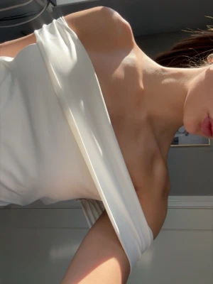 Vit axelbandslös tubtopp - Snygg vit axelbandslös tubtopp i mjukt material. Köpt i usa men vet ej vart ifrån. Toppen har en enkel och stilren design som sitter tight runt kroppen och passar perfekt till jeans eller kjol. Perfekt för varma dagar eller lager på lager.