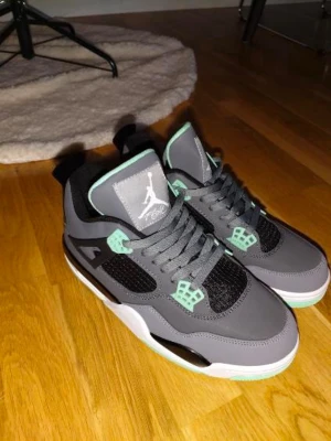 Nike Air Jordan 4 Retro Grå/Mint - Säljer ett par Nike Air Jordan 4 Retro i grått med mintgröna detaljer och svart mesh. Skorna har klassisk snörning, Jumpman-logga på plösen och yttersulan i mintgrönt och svart. Tillverkade i syntet och skinn för en clean look. Använda max 1-2 ggr som.nya  