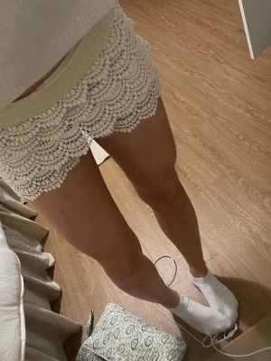 Vita virkade shorts med spetsdetaljer - Säljer ett par vita virkade shorts med snygga spetsdetaljer och elastisk midja. 