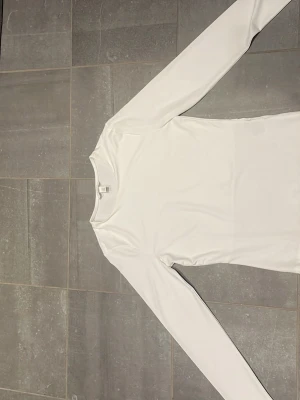 Vit långärmad topp från H&M - En stilren vit långärmad topp från H&M i mjukt material. Toppen har rund halsringning och en slim passform som sitter snyggt på kroppen. Perfekt att styla med jeans eller kjol för en clean look. Extra material vid bröstet så att det inte syns igenom. Kom gärna med prisförslag 