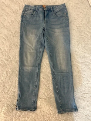 Ljusblå jeans med dragkedja (strl: 30/30) - Snygga ljusblå skinny jeans med dragkedjor vid bensluten och klassiska fem fickor. Jeansen har en lätt tvättad look och är tillverkade i stretchigt denim för en bekväm passform. 