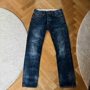 Dobber blå jeans 30/32 - Snygga blå jeans från Dobber i klassisk tvätt med slitningar och kontrastsömmar. Modellen har raka ben och femficksdesign. Perfekta för dig som gillar en tidlös denimlook. Märke: Dobber Original Denim. Pris diskuterbart 
