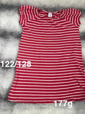 Röd- och vitrandig klänning Polarn o pyret  - Söt klänning från Polarn o pyret i röd och vit randig design. Klänningen har korta puffärmar och rundad hals med resår. Perfekt för en avslappnad och trendig look.🌸Fint använt skick. Storlek 122/128 