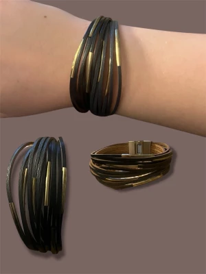 Svart läderarmband med gulddetaljer - Snyggt svart armband i flera tunna läderremmar med guldfärgade metallinslag. Armbandet har ett modernt och stilrent uttryck och stängs med ett magnetlås i metall. Perfekt accessoar för att lyfta din outfit. Helt nytt-nypris 259