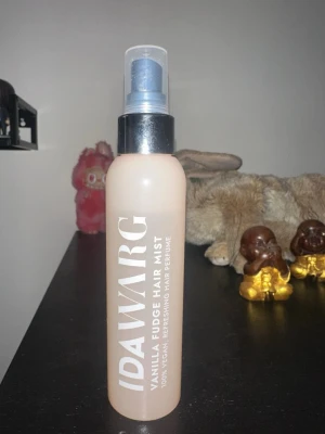 Ida Warg Vanilla Fudge Hair Mist - Fräsch hårmist från Ida Warg med doft av vanilj och fudge. Kommer i en beige plastflaska med svart spraylock och vit text. 100% vegansk hårparfym som ger håret en söt och fräsch doft. Perfekt att ha i väskan för en snabb uppfräschning.