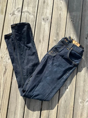 Nudie jeans Grim Tim - W32 L34. Snygga mörkblå jeans med raka ben och klassiska kontrastsömmar. Jeansen har fem fickor och gylf med knapp och dragkedja. Perfekta till en avslappnad stil och tillverkade i denim. Passar dig som gillar en tidlös look.