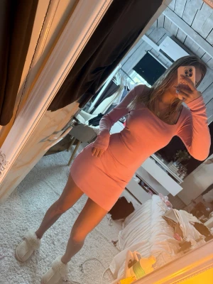 Rosa långärmad kortklänning - Säljer en tight, rosa kortklänning med lång ärm och rundad halsringning. Klänningen har en enkel och stilren design som framhäver figuren. Perfekt för dig som gillar en feminin och trendig look.
