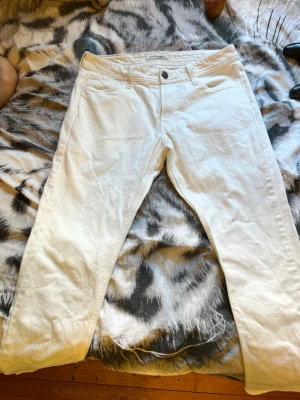 Vita jeans  - Säljer ett par snygga vita jeans med klassisk femficksmodell och raka ben. Jeansen har normal midja och är tillverkade i ett mjukt bomullstyg med lite stretch för extra komfort. Perfekta för en fräsch och stilren look.