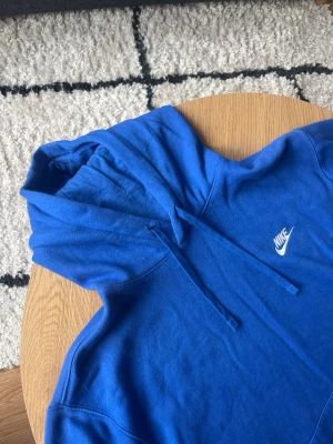 Blå Nike hoodie - Tjena👋 Säljer en snygg blå hoodie från Nike med klassisk vit logga på bröstet🧶Hoodien har huva med dragsko och en stor magficka🪡Tillverkad i mjukt bomullsmaterial och har ribbade muddar vid ärmslut och nederkant🙌 Perfekt för en avslappnad och sportig stil🤩 Vid frågor: Meddela mig📩