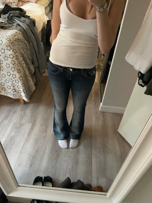 Mörkblå bootcut jeans Gina Tricot - Snygga mörkblå bootcut jeans från Gina Tricot med slitningar och kontrastsömmar. Klassisk femficksmodell och låg midja. Perfekta till en avslappnad och trendig look. 