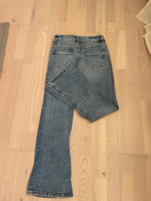 Blå bootcut jeans - Säljer ett par blå bootcut jeans med rå kant nertill och klassiska fem fickor. Jeansen har en lätt tvättad look och normalhög midja. Perfekta för en avslappnad och trendig stil. Ordinarie pris: Ca 250 kr. Har använt väldigt få gånger.