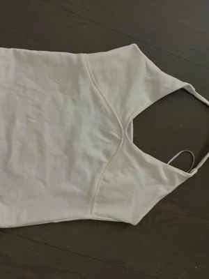 Vit ärmlös linnetopp med knyt - Säljer en stilren vit linnetopp med halterneck och knyt i nacken. Toppen är ärmlös och har en enkel, clean design som passar perfekt till sommaren. Materialet känns lätt och luftigt, perfekt för varma dagar.
