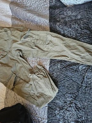 Olivgröna/beige cargobyxor Jack & Jones - Snygga olivgröna/beige cargobyxor från Jack & Jones med flera praktiska fickor på sidorna. Byxorna har klassisk cargomodell med raka ben och detaljerade sömmar. Perfekta för en avslappnad streetstil. Materialet är bomull för skön känsla.