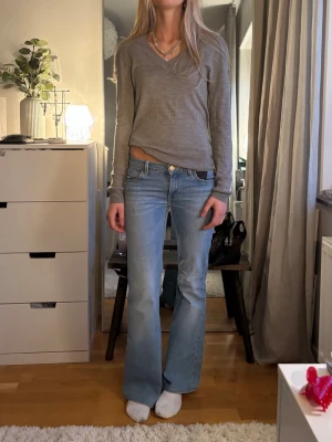 Grå kashmire tröja med v-ringning - En enkel och stilren grå långärmad tröja med v-ringning. Tröjan har en avslappnad passform och är tillverkad i ett tunt, mjukt material som passar perfekt till jeans eller kjol. Perfekt för lager-på-lager och vardagsstil.