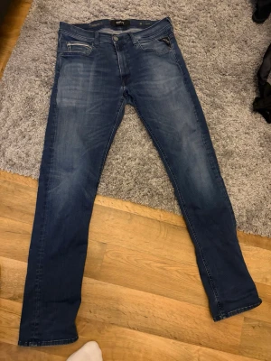 Replay jeans Grover  - Snygga blå jeans från Replay med raka ben och klassisk femficksdesign. Jeansen har slitningar och ljusare partier framtill och baktill för en cool, använd look. Märkespatch i läder bak i midjan och diskret logga på bakfickan. Tillverkade i bomull. Storleken är mindre än det som står!
