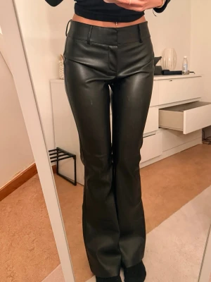 Svarta skinnbyxor från Gina Tricot - Snygga svarta low waist skinnbyxor från Gina Tricot i storlek 36. Byxorna har en tight passform upptill och lätt utsvängda ben, med klassisk midja och hällor för skärp. Perfekta för en trendig och edgy look.