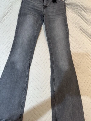 Grå bootcut jeans från 157 - Säljer ett par grå bootcut jeans från 157 med klassisk femficksmodell och dragkedja. Jeansen har en snygg tvättad look och är tillverkade i mjukt denimtyg. Perfekta för dig som gillar en avslappnad men trendig stil.