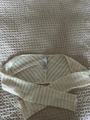 Beige bolerotopp från Bershka - Snygg beige bolerotopp från Bershka i stickat material och har ett genomgående hålmönster som ger en luftig känsla. Perfekt att styla över ett linne eller klänning.