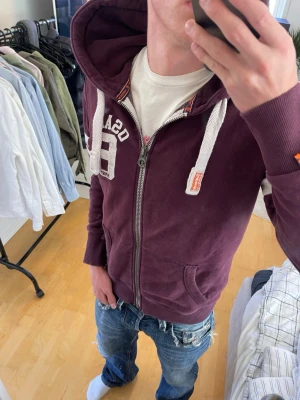 Vinröd Vintage 2000s SuperDry zip hoodie (sällsynt) - Säljer nu denna sjukt snygga Vintage 2000s SuperDry hoodie! Passar till allt och har en perfekt passform. Säljs ej längre i butik och är därav mycket eftertraktad😊 passar S perfekt ! Skriv vid funderingar 🤝