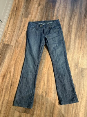Mörkblå bootcut jeans från Vila - Säljer ett par mörkblå bootcut jeans från Vila med klassisk femficksdesign och subtila sömmar. Jeansen har normal midja och raka ben med lätt utsvängning nedtill. Materialet är denim i bomull med lite stretch för skön passform.