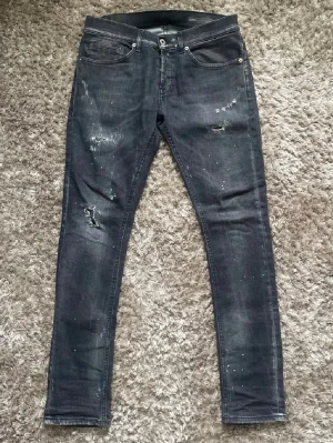 Svarta slim fit jeans med slitningar - Snygga svarta jeans från dondup, med en go avslappnad look. Storlek 31 men passar även 30! Använda ett få par gånger och är i nyskick, skriv om ni har frågor!!!