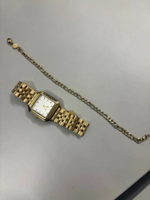 Guldig fyrkantig klocka från Milani - Stilren klocka från Milani i guldigt metallutförande med fyrkantig urtavla och vit bakgrund. Länken är klassiskt designad och ger en lyxig känsla. Perfekt accessoar för att lyfta din outfit.