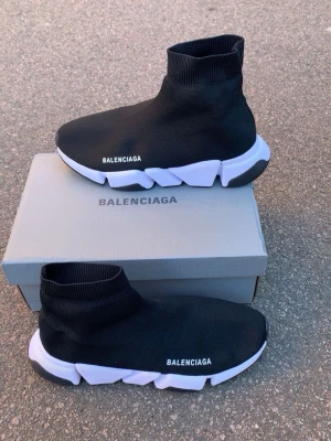 Balenciaga Speed Trainer svarta sneakers - Svarta Balenciaga Speed Trainer sneakers med vit och svart chunky sula. Stickad ovandel i stretchigt tyg som sitter som en strumpa runt foten. Balenciaga-logga på sidan och unik futuristisk design. Perfekta för dig som vill ha en modern och trendig look.