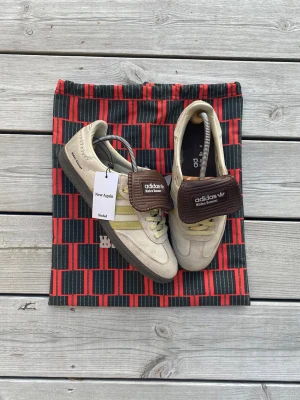 Adidas x Wales Bonner - Erctin Brown EU44 - Tja! Säljer dessa riktigt feta skor från Adidas x Wales Bonner i en unik och snygg colorway. I storlek 44 EU, någon skavank (se bild) men inte något man märker med de på.  Hör av dig ifall du har något intressant byte  ✅ Proffesionellt äktighetsverifierad av Vinted och har även gått genom Vestiaire Collectives verifikation (kan skicka orderhistorik).  ✅ Dustbag och äktighetsbevis medföljer!  🌟 Hör av dig för fler bilder eller prisförslag!