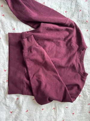 Vinröd sweatshirt från Gina Tricot - Mysig vinröd sweatshirt från Gina Tricot med rund halsringning och ribbade muddar vid ärmslut och nederkant. Perfekt för dig som gillar en enkel och stilren look. Tillverkad i mjukt material som känns skönt mot huden.