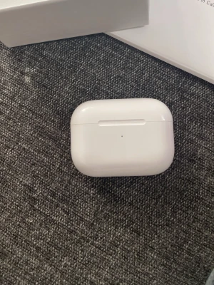 Apple AirPods Pro 2 med laddningsetui - Säljer ett par vita Apple AirPods Pro 2 med trådlöst laddningsetui. Hörlurarna har en stilren och kompakt design i blank plast och levererar grymt ljud med brusreducering. Perfekta för musik, poddar och samtal på språng.