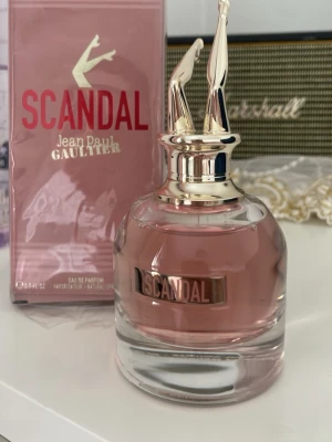Scandal parfym från Jean Paul Gaultier - Scandal från Jean Paul Gaultier är en lyxig parfym i en rund glasflaska med rosa doftvätska och en unik guldfärgad kork formad som ett par ben. Förpackningen är rosa med guld- och röda detaljer. Perfekt för dig som gillar statement-dofter och snygg design.