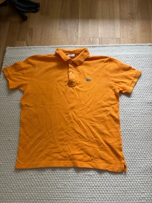 Lacoste piké - Säljer denna Lacoste piken, den är fint skick förutom små fläckar som syns svagt, syns mer när man håller tröjan mot ljus, se sista bilden. Nypris: 1099kr Storlek 5/L Mått: Axel-Axel 44cm Armhåla-Armhåla 51cm Längd 64cm
