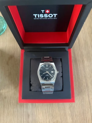 Tissot prx 80 blå urtavla - Stilren Tissot PRX klocka i silver med länkarmband i metall och blå urtavla. Klockan har datumvisning och klassisk design med tydliga index och visare. Perfekt accessoar för dig som gillar tidlös och elegant stil.