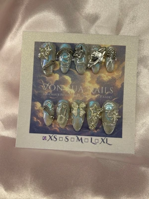 Astra (XS);Medium Almond - Unika handgjorda press-on naglar i skimrande blått med silverdetaljer och 3D-dekorationer som stjärnor, planeter och månar. Medium långa och mandelformade och handgjorda i XS: 14 mm, 11 mm, 11,5 mm, 10 mm, 8 mm, perfekta för dig som vill ha en kreativ och galaktisk look.