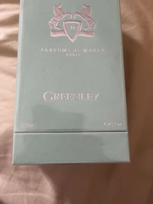 Parfums de Marly Greenley 125ml - Greenley från Parfums de Marly är en exklusiv parfym i en stilren, ljusgrön kartong med silverdetaljer och logotyp med två hästar. Flaskan rymmer 125 ml och doften är känd för sin fräscha och eleganta karaktär. Perfekt för dig som gillar lyxiga och moderna parfymer. Helt ny oöppnad