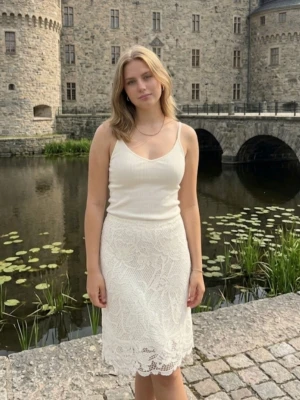 Vit spetskjol med blommönster - Säljer en vit, knälång kjol i spets med blommigt mönster. Kjolen har en rak passform och är fodrad under spetsen för extra komfort. Perfekt för sommarens alla tillfällen och ger en romantisk vibe till din outfit.