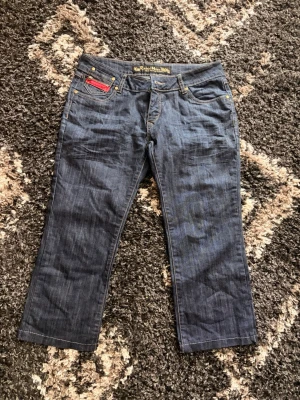 Mörkblå Capri jeans vintage  - Snygga mörkblå Capri jeans som är jätte trendiga nu dessutom vintage från tidiga 2000 talet. Strl är lite oklar men skulle säga L och kanske M. Jeansen har en unik ficka framtill med röd dragkedjedetalj och kontrastsömmar💙