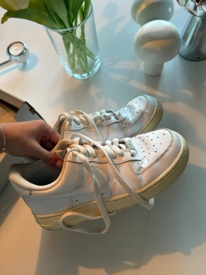 Nike Air Force 1 - Klassiska vita Nike Air Force 1 sneakers i lågt snitt med ovandel i läder och sula i gummi. Ikonisk design med perforerad tå och tydlig swoosh på sidan. Perfekta för en clean och stilren look. Välanvända och inköpta för ca 4 år sedan på Nike.