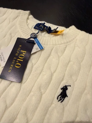 Vit kabelstickad tröja Polo Ralph Lauren - Kabelstickad creme tröja från Ralph lauren. Säljer då den inte passar. Pris kan diskuteras, skriv om det undras något! 